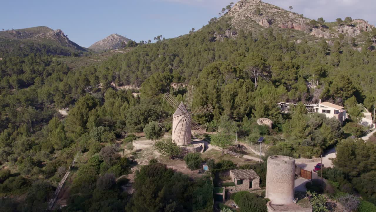 Vista aerea dello storico mulino a vento Moli de Sa Planeta in campagna ad Andratx, Spagna, con splendida illuminazione dell'alba o del tramonto, atmosfera serena, riprese drone di alta qualità che esaltano la bellezza naturale