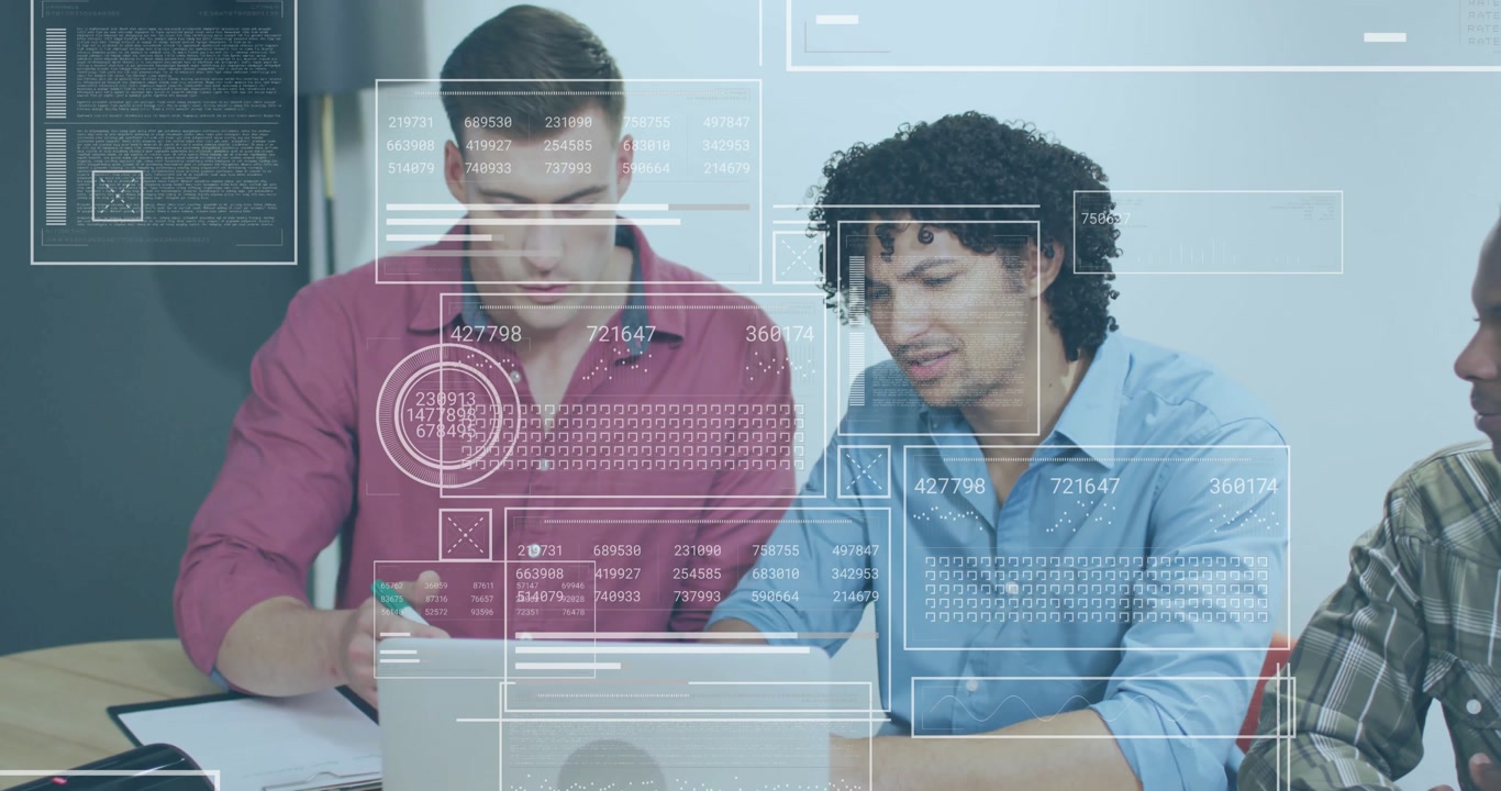 Analyst taking notes while colleague monitoring laptop activating data overlays for tech analysis