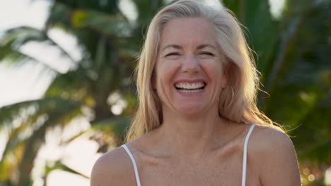 Beautiful-mature-woman-with-blonde-and-gray-hair-lifts-up-granny-glasses-and-smiles-and-laughs-at-camera