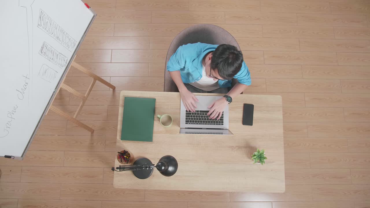 위쪽 뷰  아웃 : 집에 있는 스마트폰 에 노트북으로 타입하는 화이트보드 의 나무 책상 에 앉아있는 아시아 남자의 허리 통증
