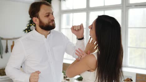 feliz y atractiva pareja joven enamorada bailan juntos en su elegante apartamento junto al árbol de navidad. encantadora familia joven en