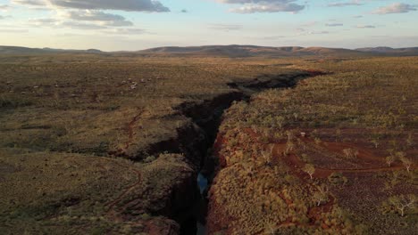 aerial wide shot of highlands in national park of australia during sunset time - mountain range and campsite in background