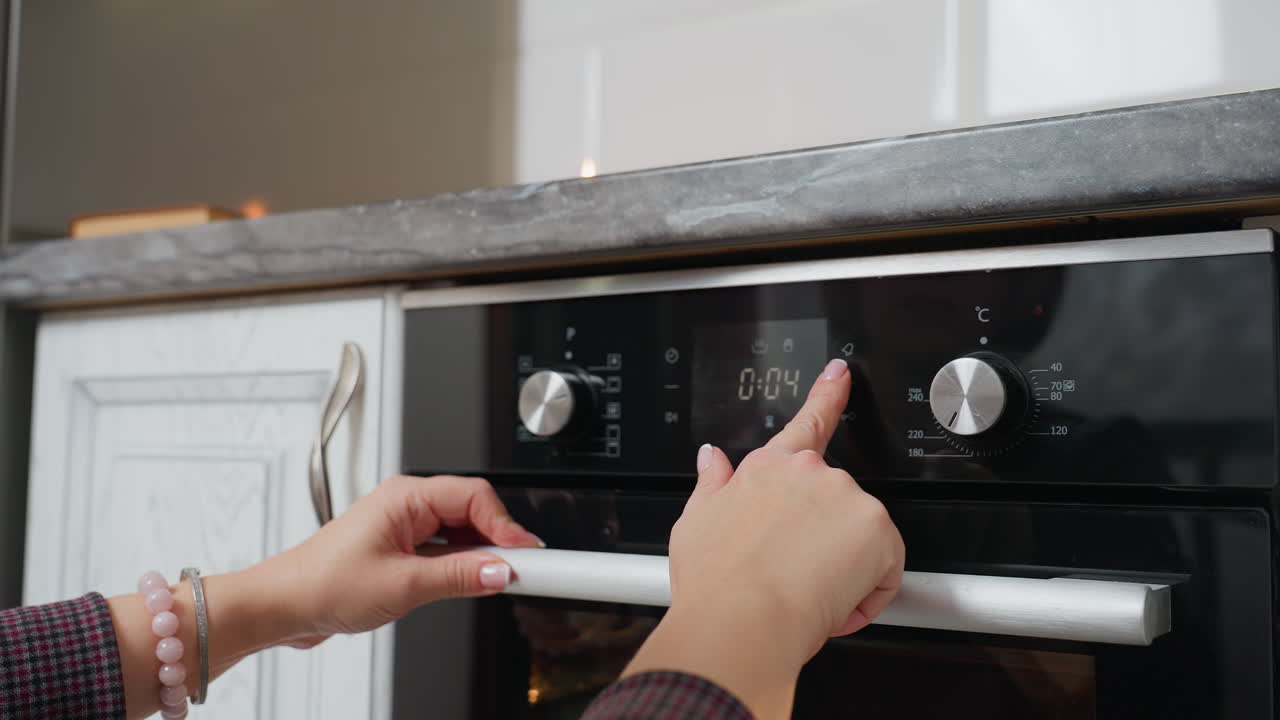Primo piano di una donna che utilizza i comandi digitali di un forno, regolando la temperatura o il timer in una cucina moderna con tecnologia avanzata per cuocere biscotti o preparare cibo