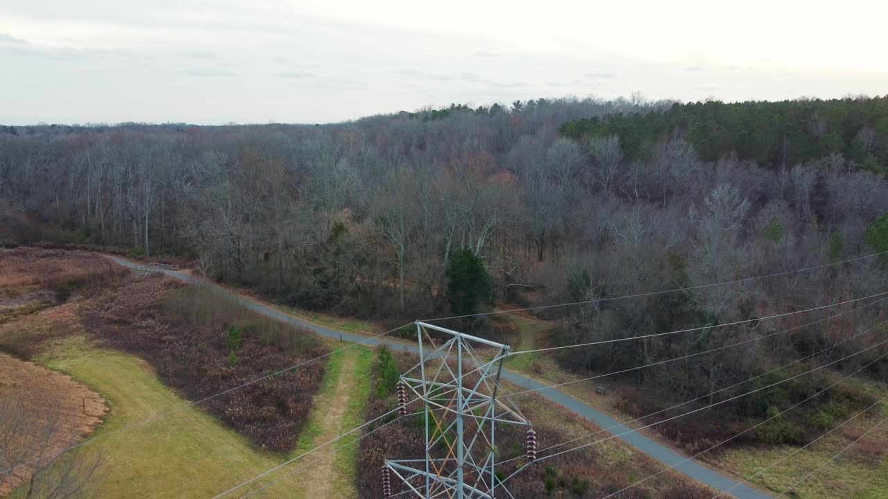 Drone revealing a close-up of a high-voltage power line tower transporting energy in Abersham Park near Davidson, North Carolina