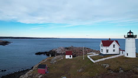 flyover of lighthouse on a rocky coastal island with rippling water and blue sky above