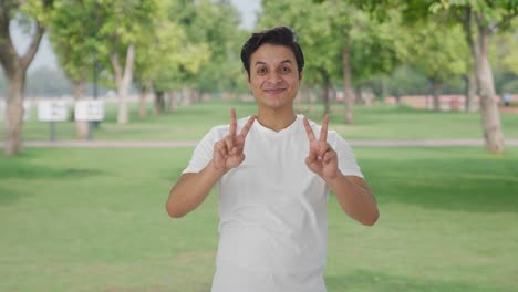 cheerful indian man showing victory sign