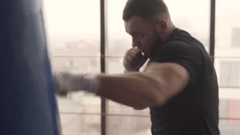 alone boxer is hitting punching bag very fast in the fitness studio