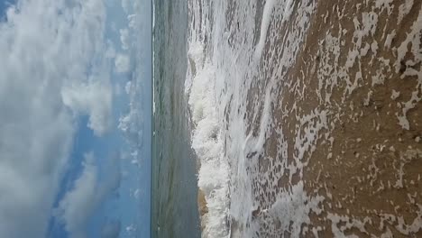 ondas verticales de movimiento lento del océano tropical que fluyen a través de la playa de arena dorada bajo un cielo nublado azul
