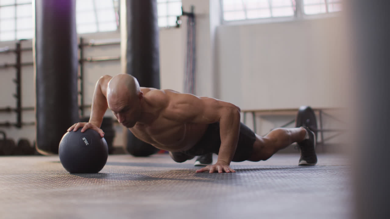 hombre caucásico en forma trabajando con la pelota de medicina en el gimnasio