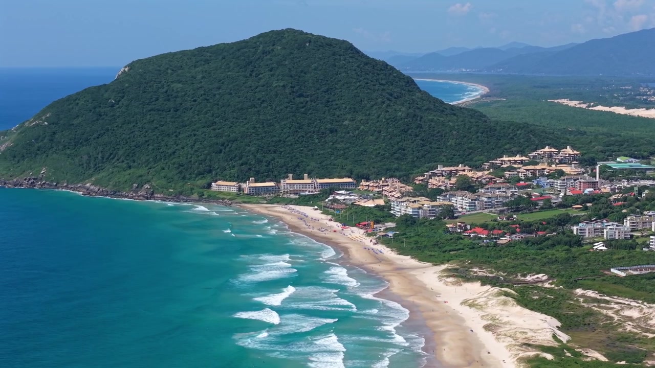 Quang cảnh bãi biển Praia do Santinho từ trên cao với những con sóng lăn tăn dọc bờ biển và sườn đồi Mirante do Santinho, Santa Catarina, Brazil.