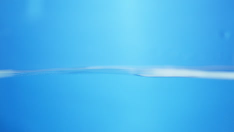 blurry shot of dancing waves of water inside a container in a blue background