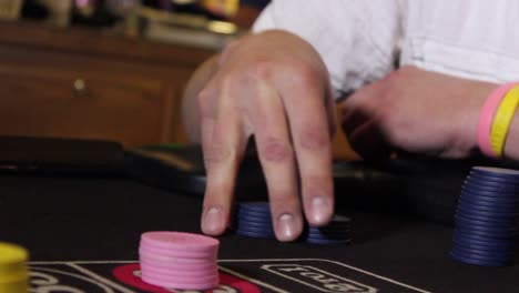 close up shot of a male hand fidgeting unmarked casino chips at a game table with some handheld camera movement