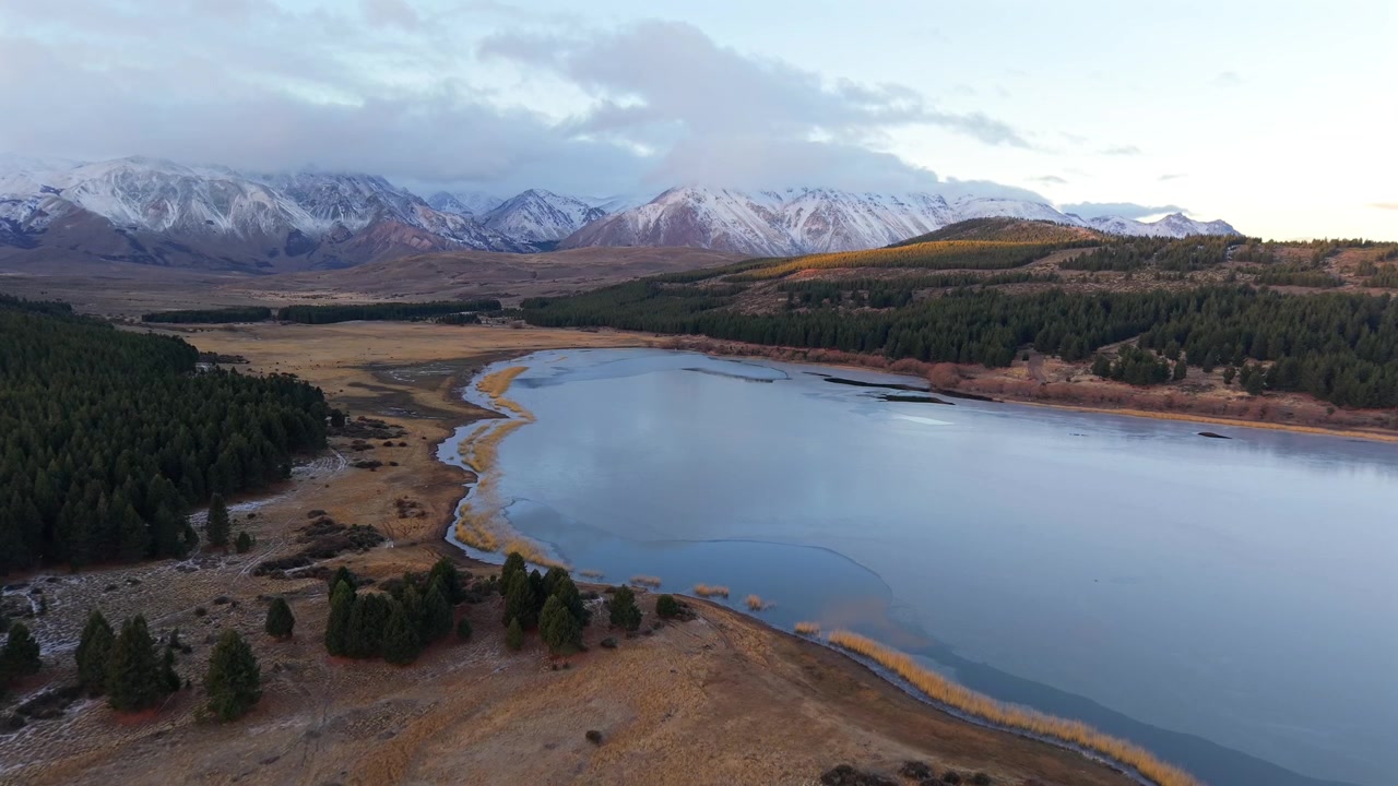 Pomalý přelet dronu nad lagunou La Zeta poblíž Esquel, Chubut, Argentina, odhalující pobřeží andského jezera, patagonský les, mokřady a zasněžené pohoří.