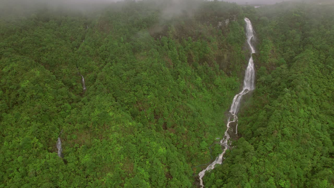 una perspectiva aérea nebulosa y nublada captura una cascada de varios niveles en medio de la atmósfera húmeda de sa pa en las montañas hoàng liên son de vietnam, donde cae con gracia sobre acantilados rocosos.