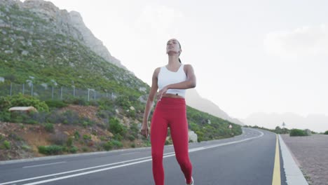 Mixed-race-woman-taking-a-break-from-running-on-a-country-road