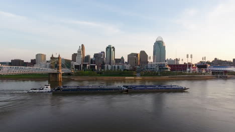 drone shot rising over the ohio river with a barge going under the john a