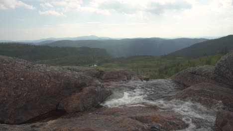 Glacial-meltwater-stream-flowing-down-rocky-mountainside,-slider-shot