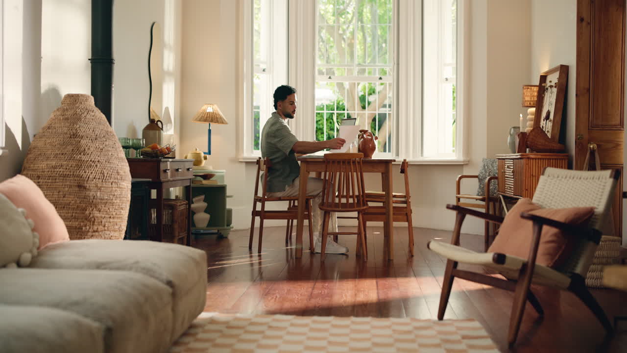 Young Man Working on Laptop at Dining Table in Bright Home
