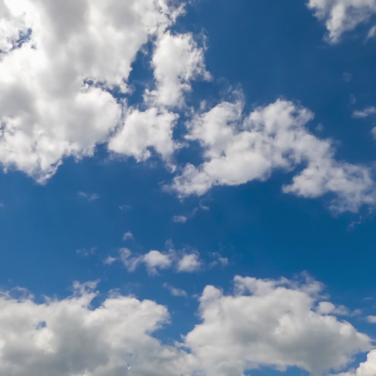 Cloudscape building in the blue sky. Soft puffy clouds flying quickly. Low angle perspective. Timelapse