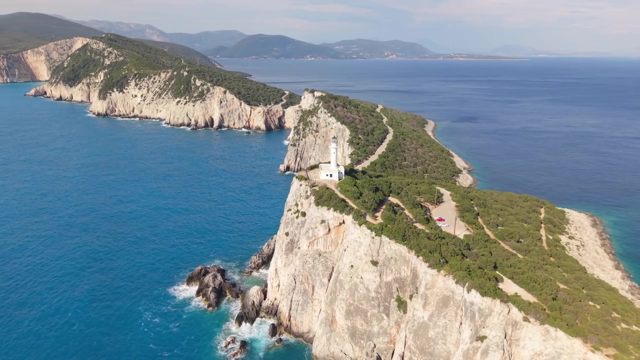Vista aerea con drone del Faro di Capo Lefkatas che si erge su drammatiche scogliere bianche sopra il Mar Ionio cristallino a Lefkada, Grecia. Paesaggio costiero mozzafiato e destinazione di viaggio estiva