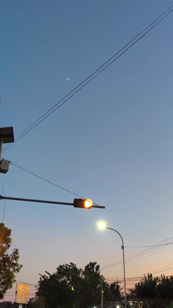 Lampu lalu lintas kuning berkedip dengan latar belakang langit senja