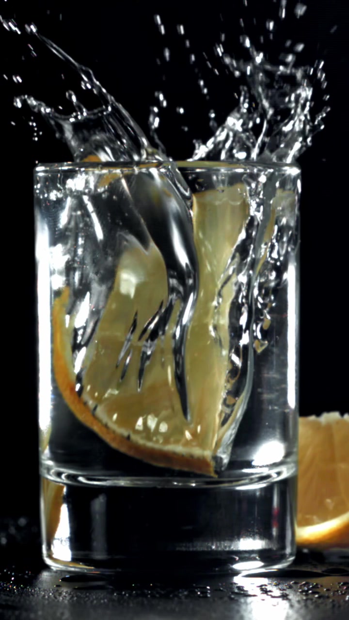 Fetta di limone che schizza in un bicchiere d'acqua al rallentatore