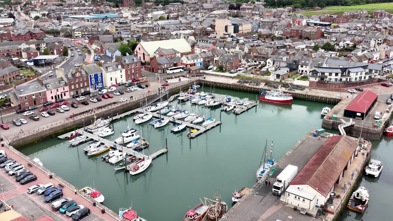 Drone captures marina, boats, waterfront buildings, and harbor activity in overcast Dundee, Scotland