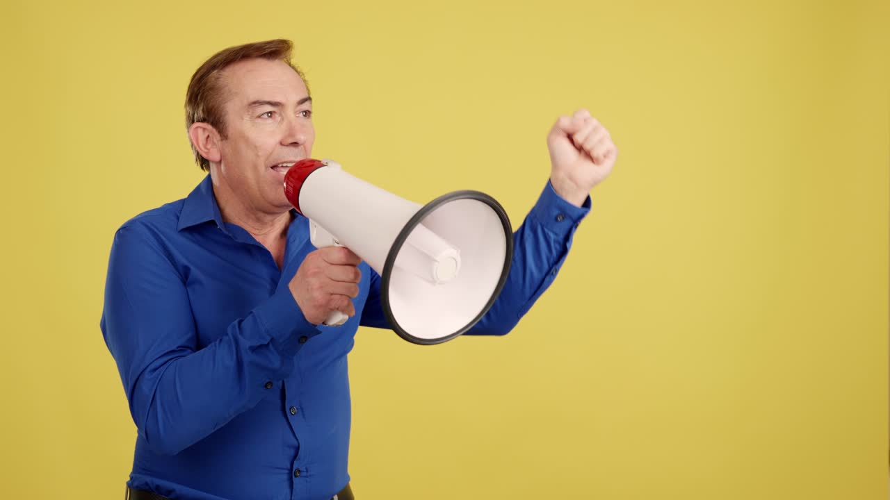 Man shouting into a megaphone against a yellow background