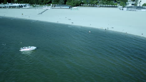 Drohnen-Umlaufbahn-Um-Ein-Schnellboot,-Das-Vor-Der-Küste-Eines-Atemberaubenden-Sandstrandes-Verankert-Ist