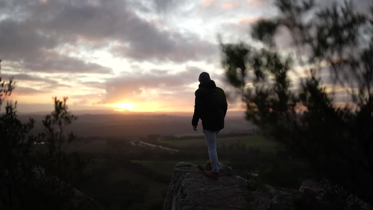 hombre caminando hacia la cima de una montaña al atardecer