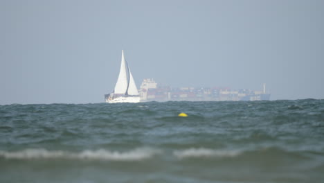 sailboat and cargo ship in the sea