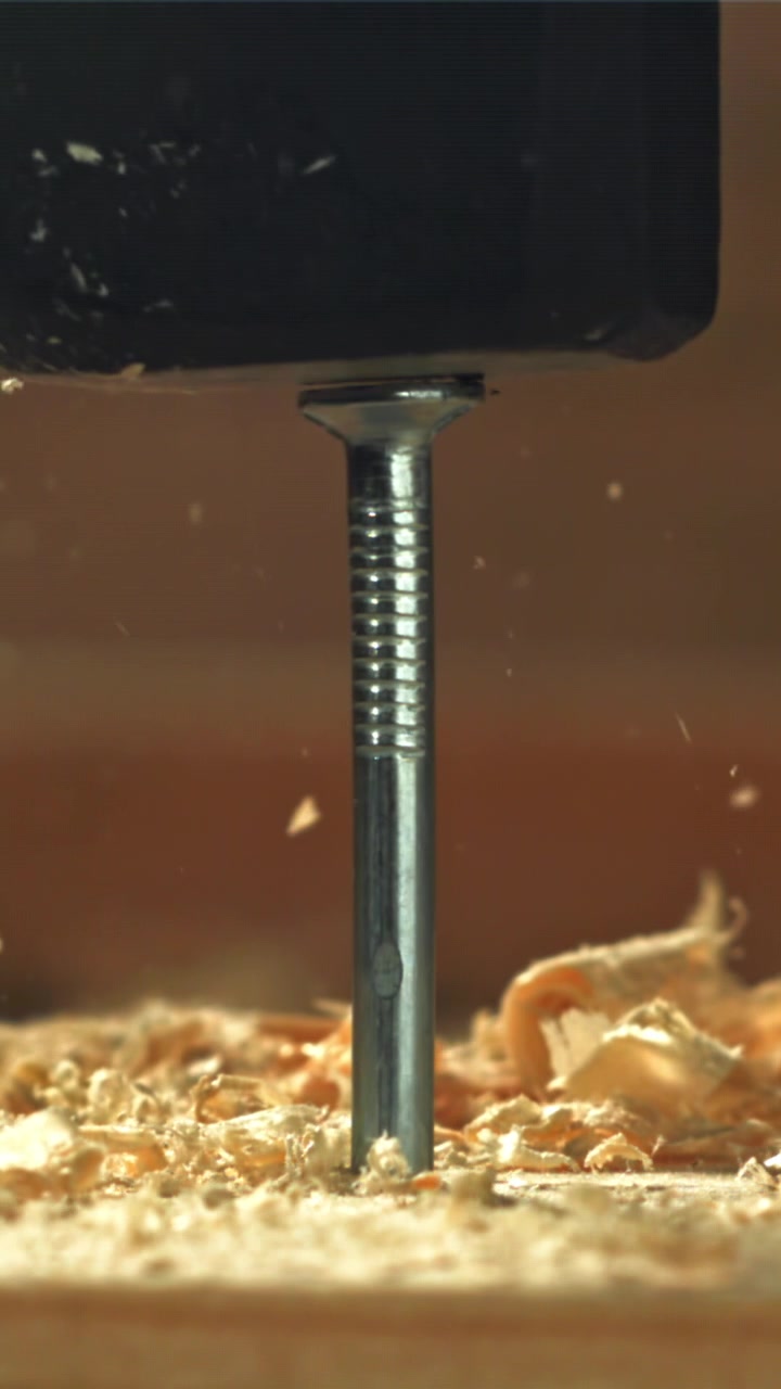 Slow Motion Hammering a Nail into Wood with Flying Sawdust