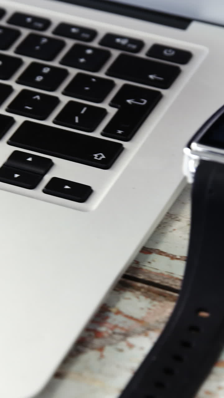 Coffee cup, laptop, smart watch on wooden plank