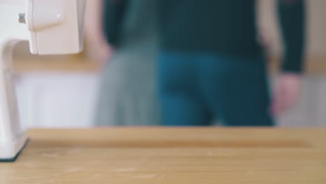 girl-takes-flour-bowl-from-home-grinder-and-man-in-kitchen