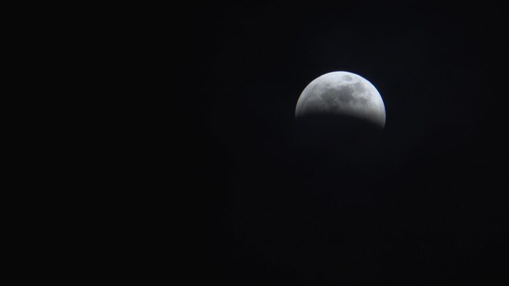 Nuvens finas passando por uma lua cheia em meio a um eclipse lunar