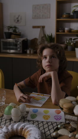 niño dibujando una tarjeta de pascua en la cocina
