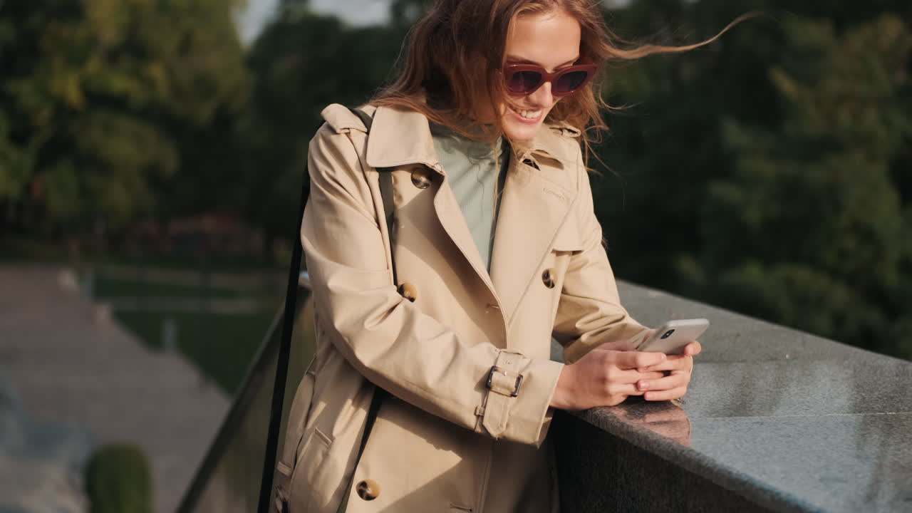Caucasian female student using smartphone outdoors.