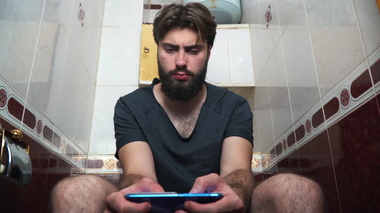 Man using smartphone in a toilet