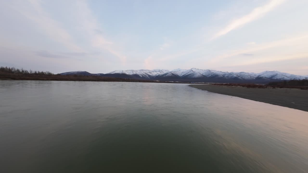 황금빛의 빛이 조용한 물 위에 춤을 추며 멀리 있는 웅장한 산을 비추는 놀라운 공중 전망에 몰입하십시오.