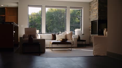 a cozy living room with large windows letting in natural light, a white sofa, and a stone fireplace