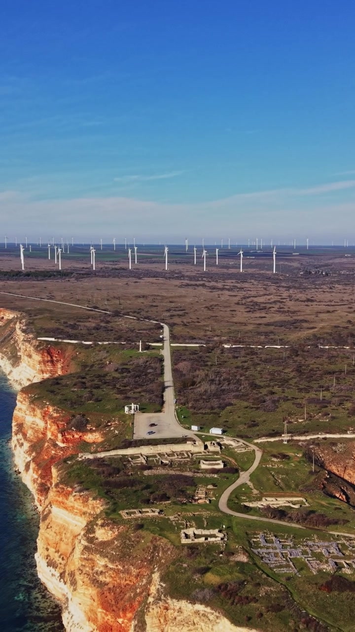 Vista de la costa con aerogeneradores bajo un cielo azul despejado durante el día