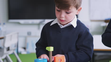 Ein-Schüler-Baut-In-Einem-Grundschulklassenzimmer-Ein-Spielzeug,-Nahaufnahme,-Fokus-Auf-Den-Vordergrund