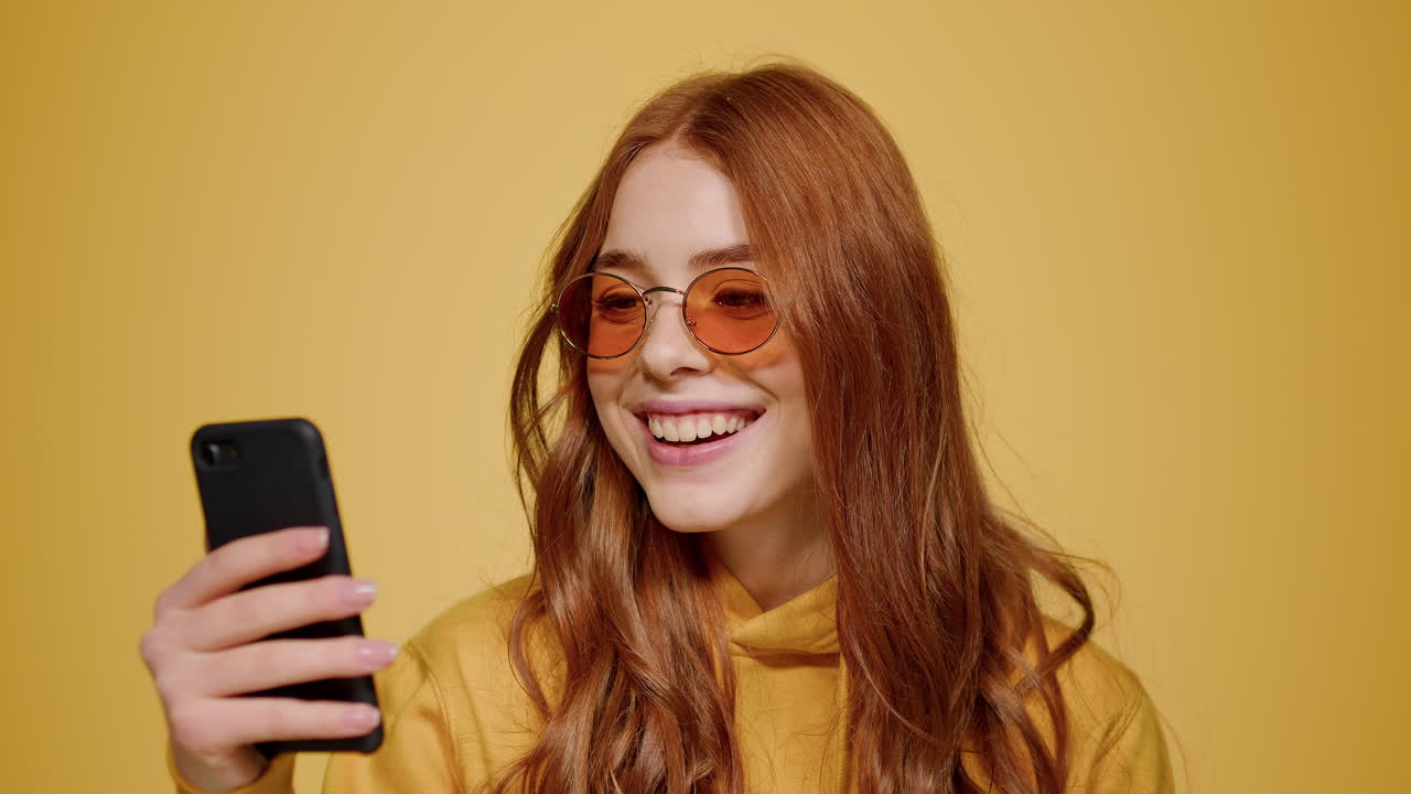 mujer alegre mirando la pantalla del teléfono en el interior. chica viendo video en el teléfono celular