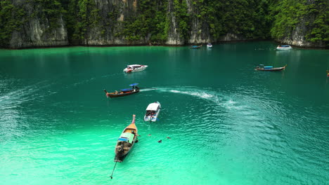 tourists sailing across phi phi island on longtail boats and speedboats, diving trips at pi leh bay , thailand, aerial view