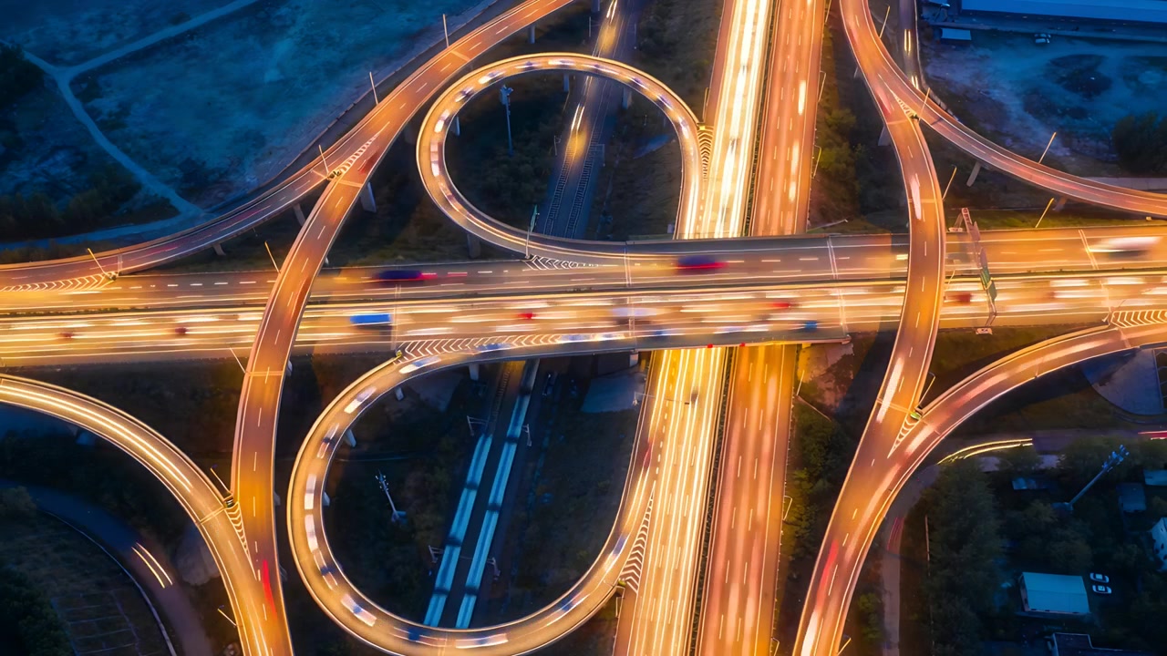 Capturing multilevel highway interchange showing vehicles moving along ramps at night, rail visible