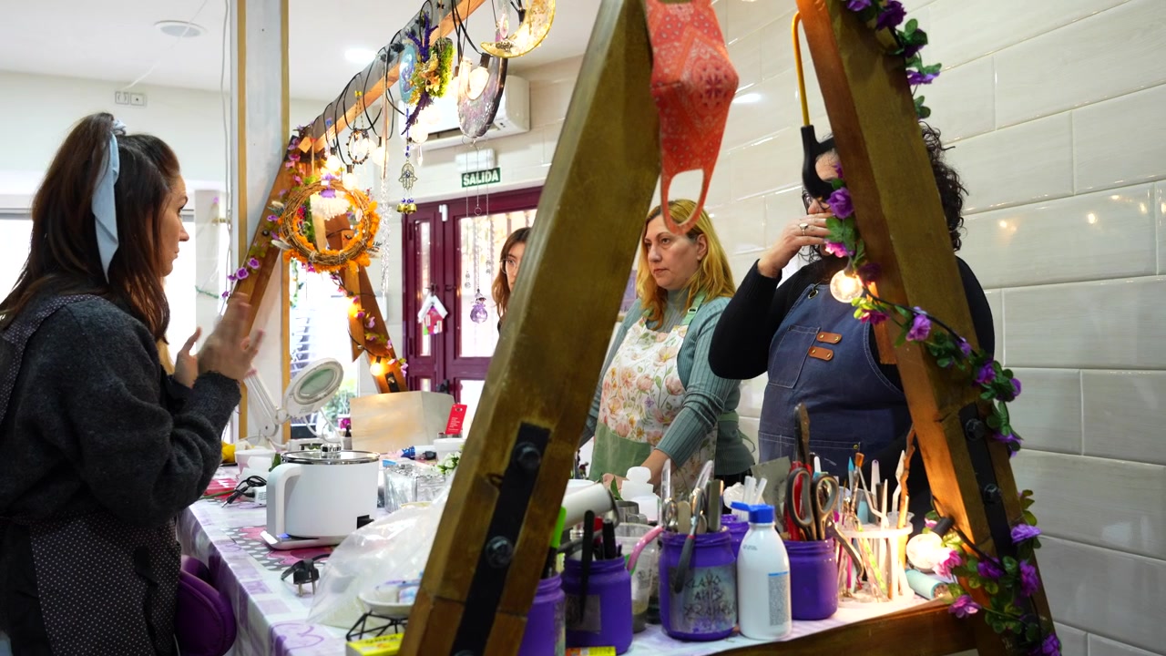 Mujeres aprendiendo y conversando durante una clase de taller creativo de fabricación de velas artesanales para pequeñas empresas.