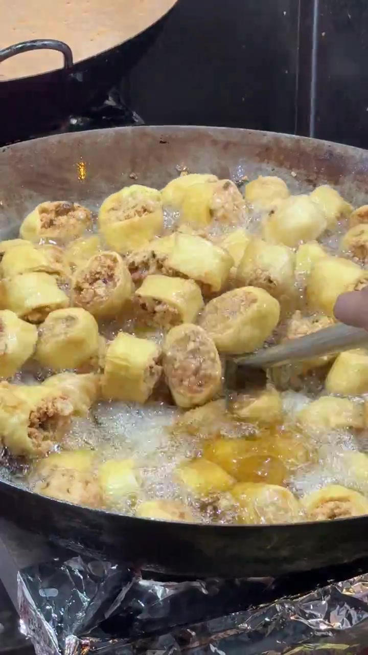 中華鍋で詰め物入り豆腐巻きを揚げるシェフ