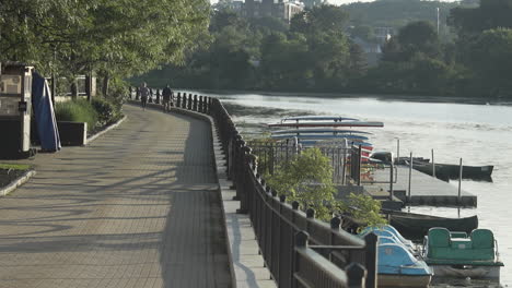 a couple strolls along the riverwalk in waltham, ma next to the charles river