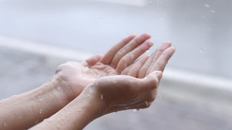 a female hands play catching rain drops on raining day caused by tropical typhoon, pure rainy spring weather, enjoying splashing purity water droplets, people touches a nature, stand on roadside