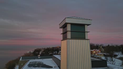 Aerial-of-Tower-obit-during-a-golden-sunrise-by-a-waterfront